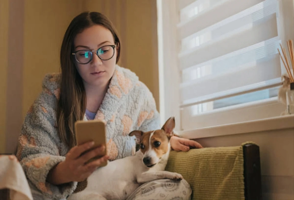 A pet owner looking concerned while researching pet care on their phone.